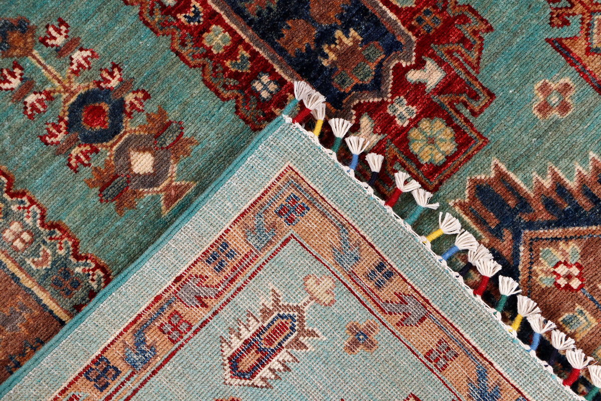 Turquoise rug corner with light border, geometric motifs, and knotted fringe
