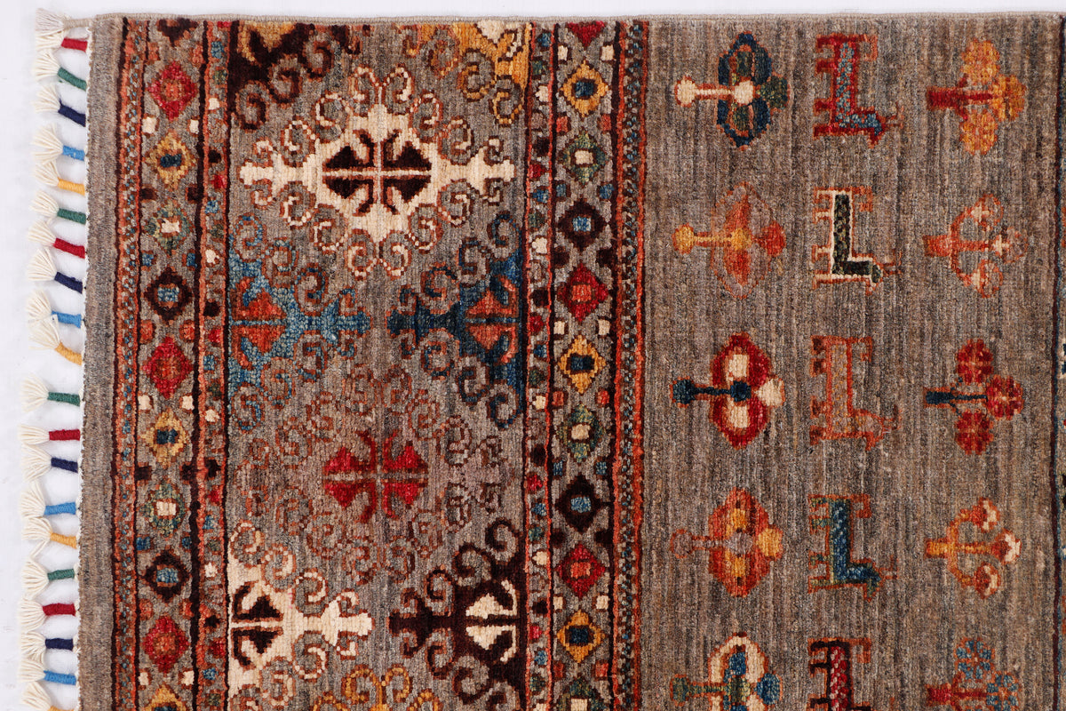 Grey rug with central medallion, geometric motifs, multicolor border, and fringed edge.