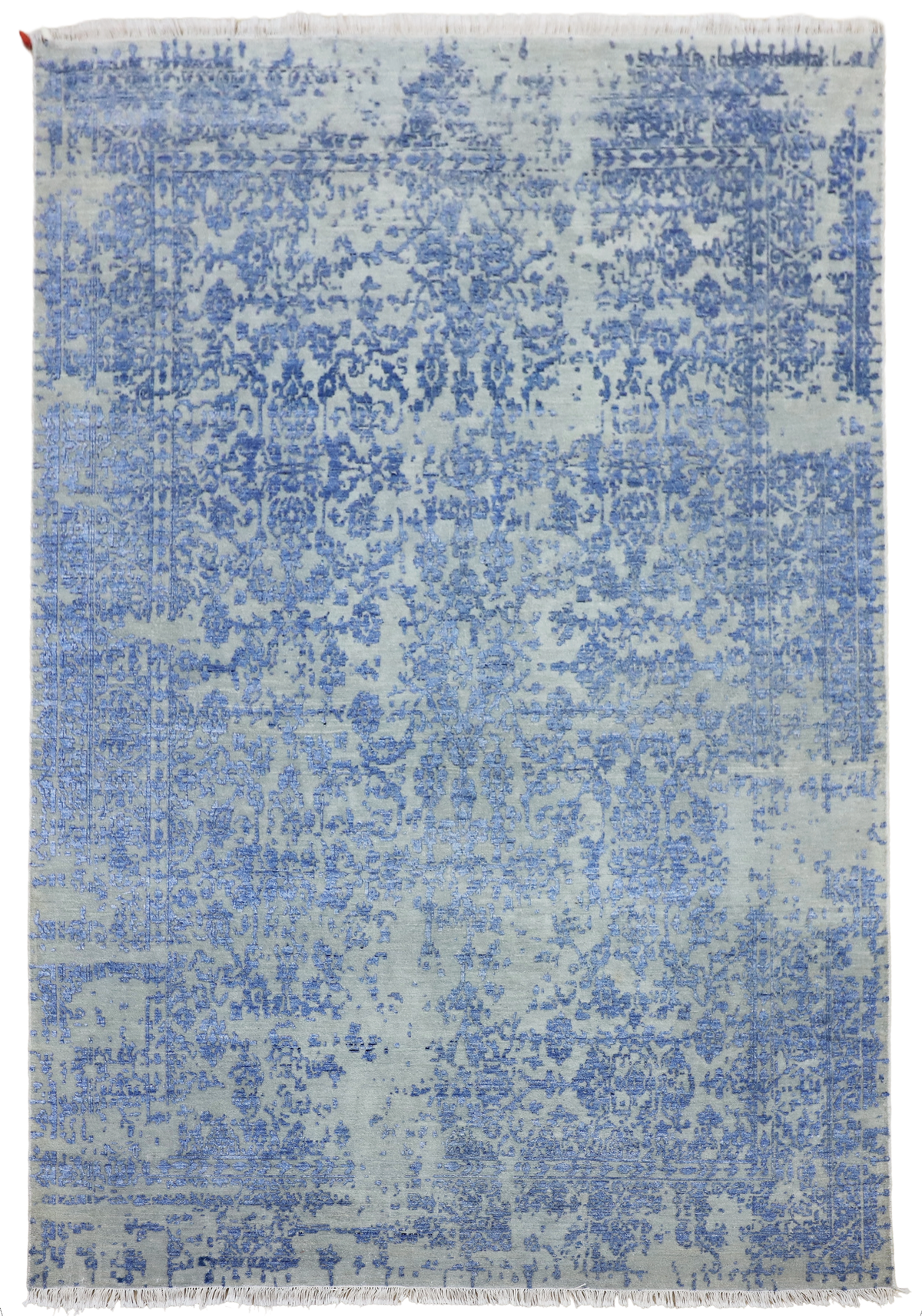 Rectangular blue mist rug with distressed allover pattern and short fringed border, flat view.