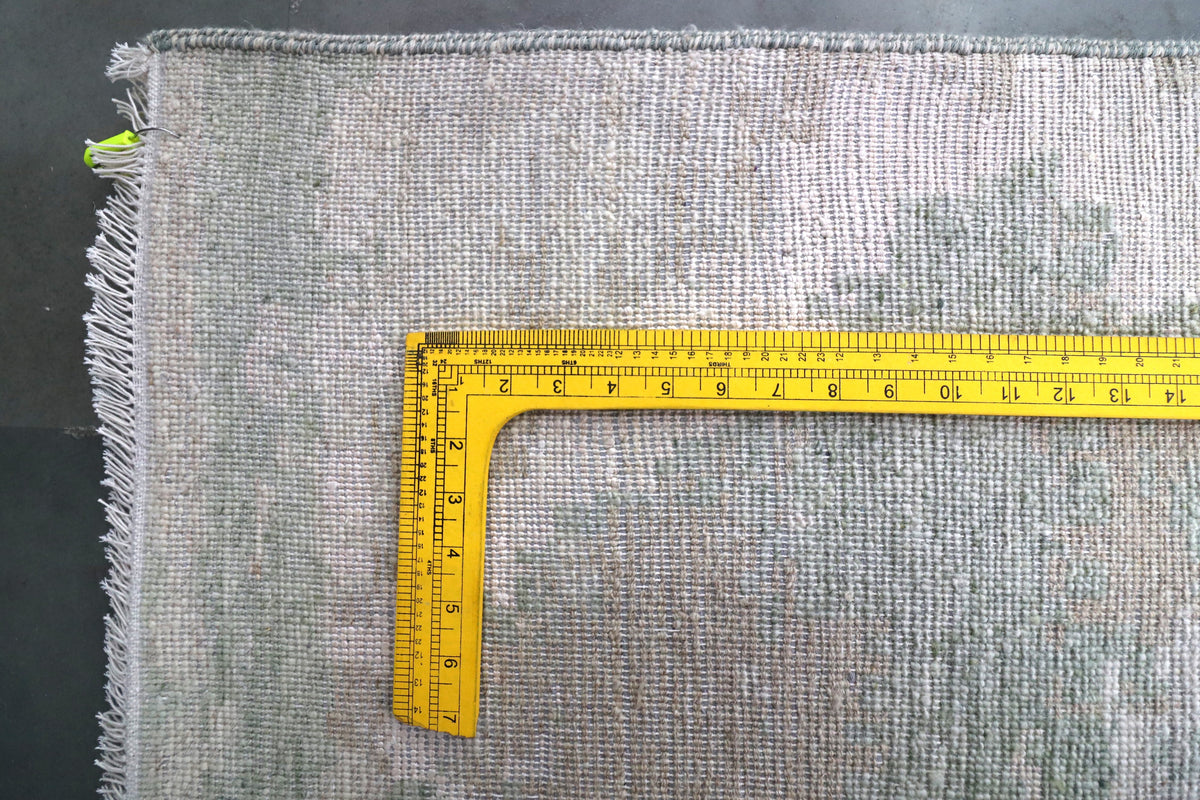 Modern rug corner with short fringe and measuring tape showing edge width