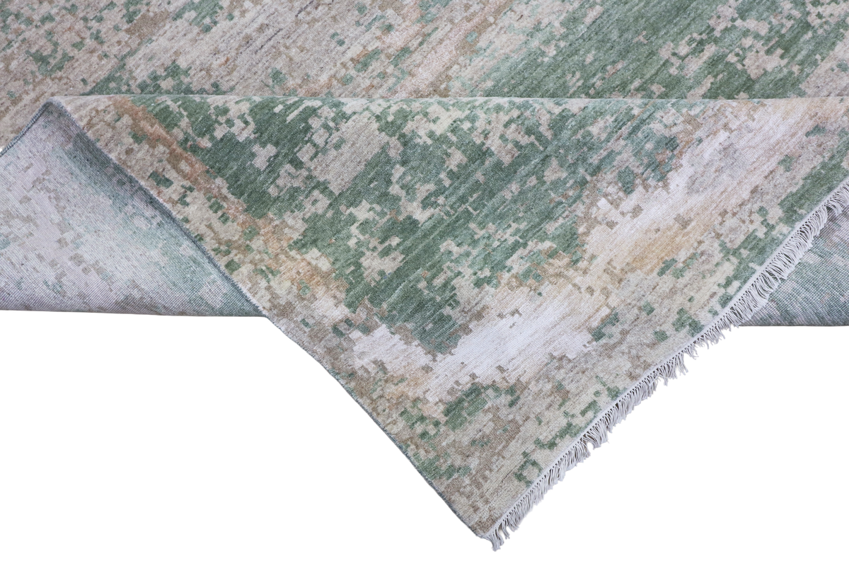 Modern abstract rug angled on white background; jade green and beige with fringed border