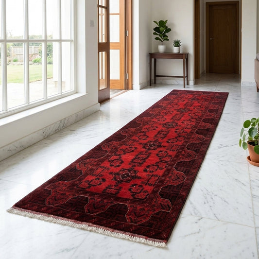 Red runner rug with dark geometric pattern and tan fringe along the edges