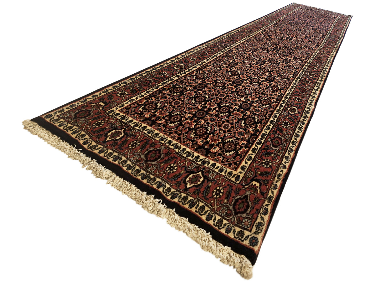 Bidjar runner rug with dark red center, patterned border stripes, and short fringe ends.