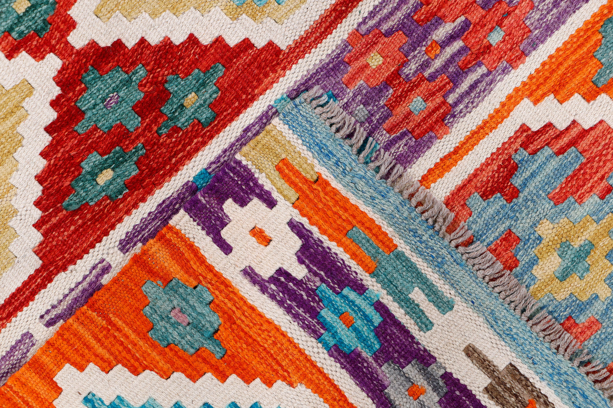 Kilim rug edge detail with orange and blue diamonds, zigzag borders, and fringe