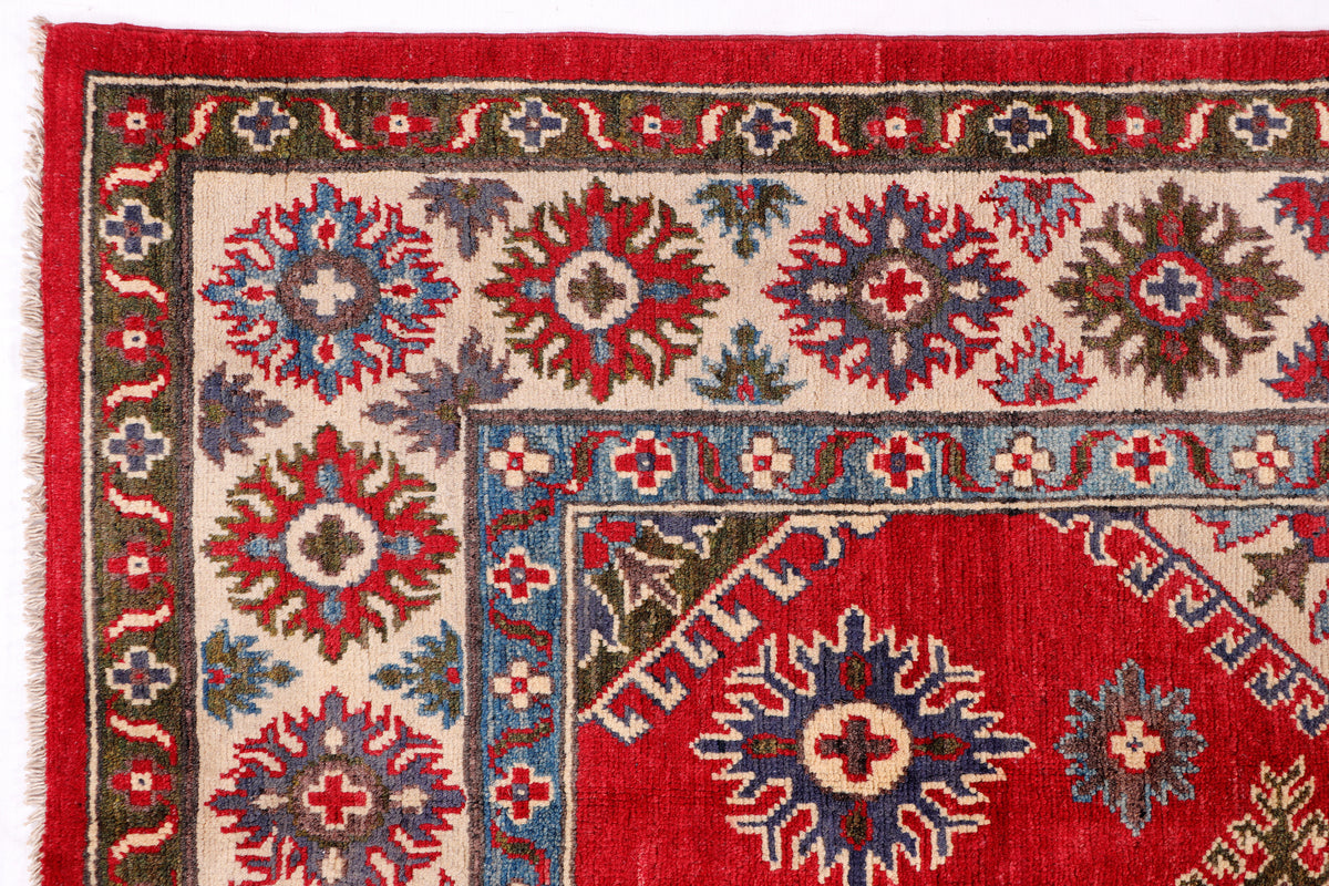 Close-up of red rug with starburst floral motifs on a beige background
