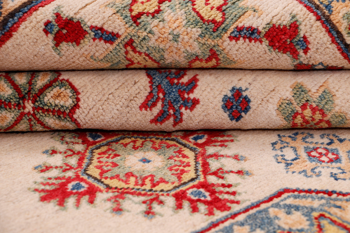 Light beige rug with red and blue motifs, rolled edge showing textured weave