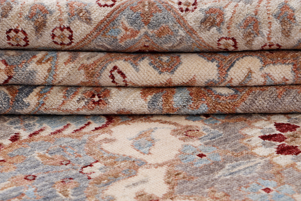 Folded rug edge close-up with beige base and blue floral motifs, rust accents