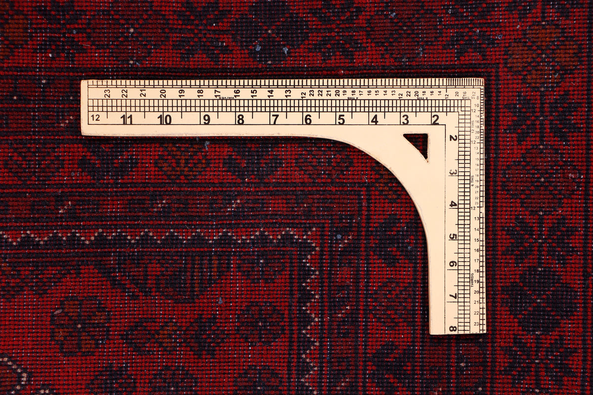 Red rug edge with measuring tape across width and detailed border pattern
