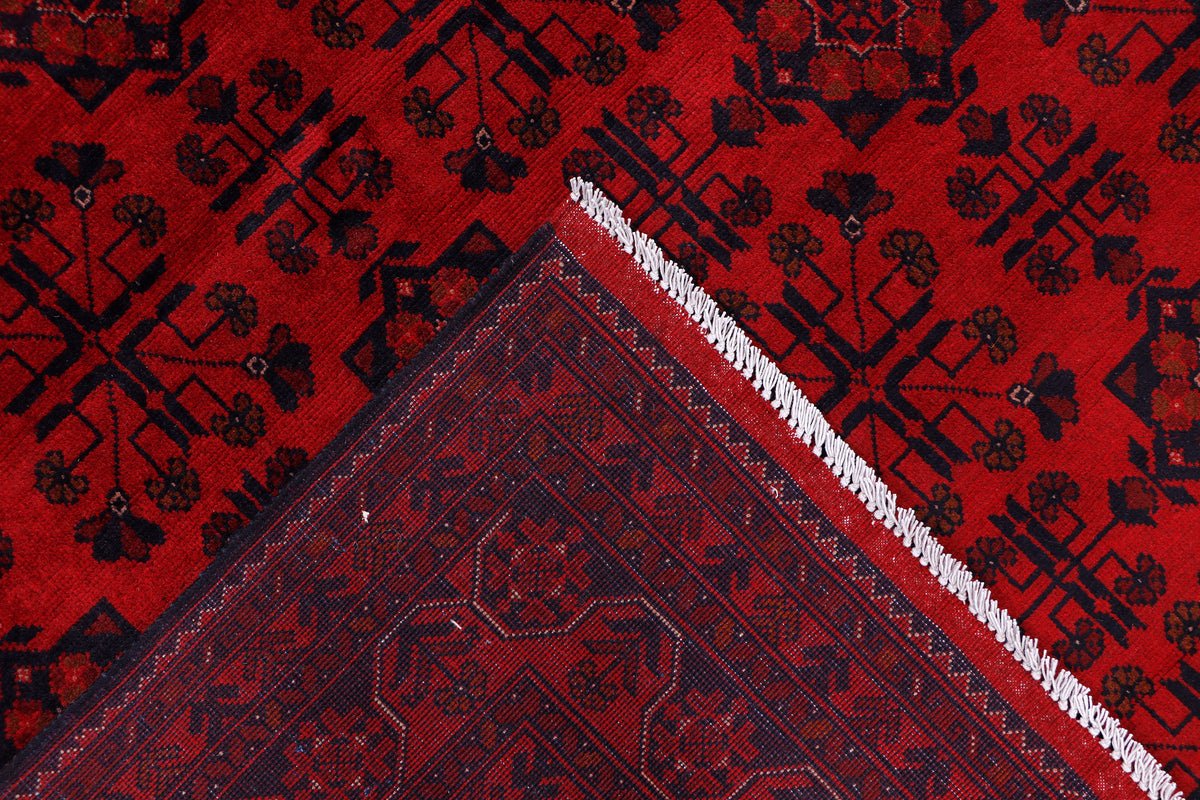Red rug corner with dark diamond pattern and short fringed edge