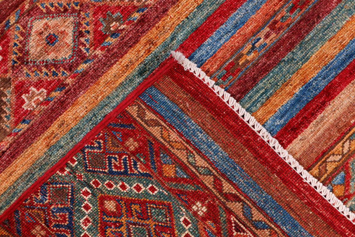 Multicolor wool rug corner with geometric motifs and white fringe edge
