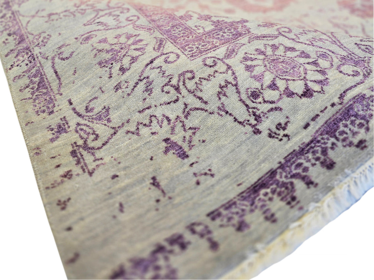 Modern beige rug close-up with purple floral motifs and fringed border edge