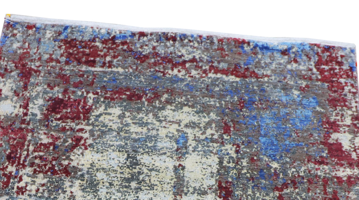 Detailed view of abstract rug surface with blue, white, and crimson distressed texture