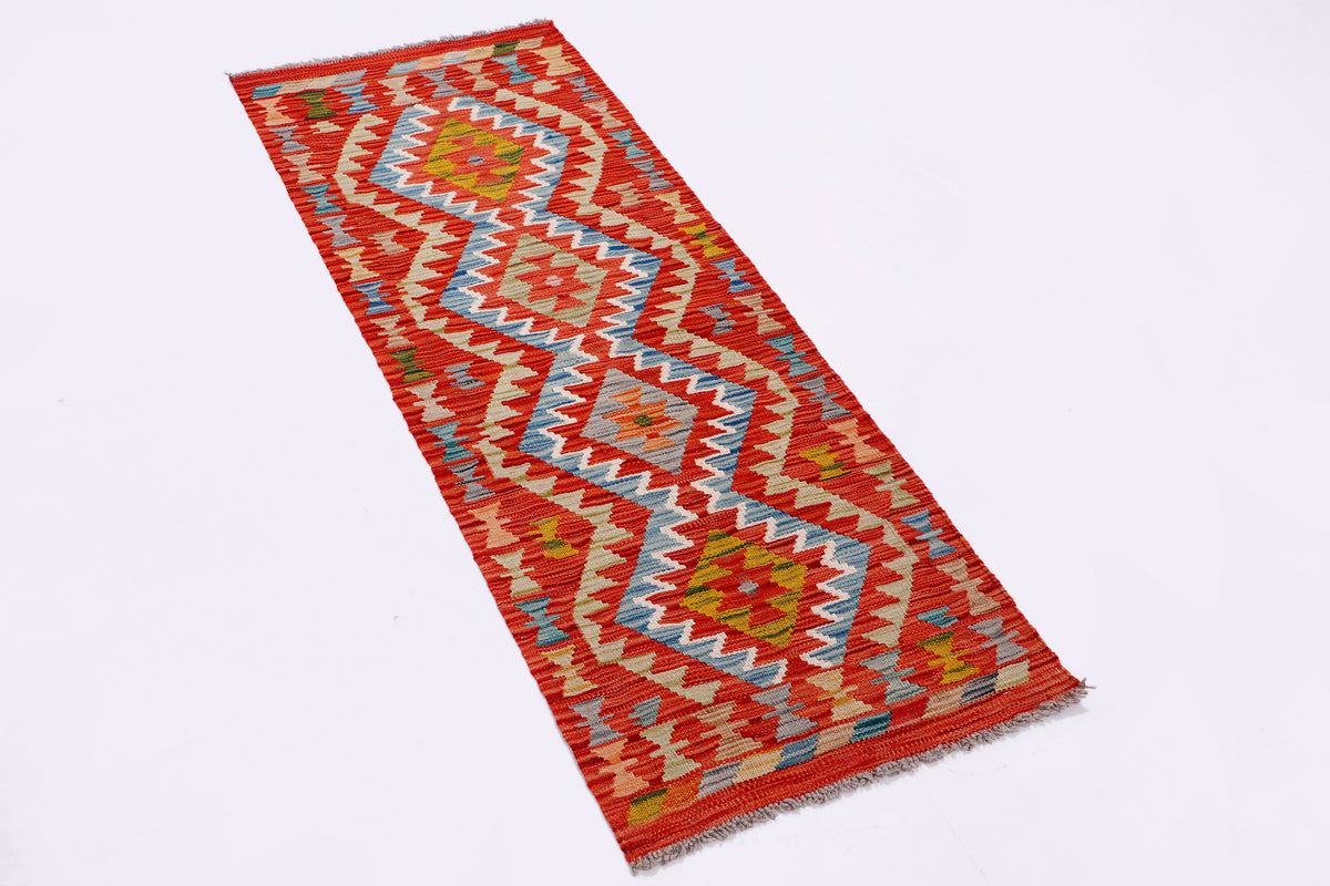 Kilim rug laid diagonally; red, cream, blue zigzag pattern with multicolor accents.
