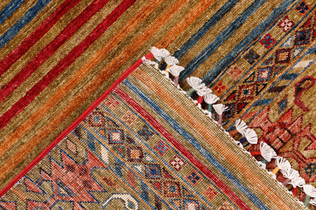 Corner of multicolor geometric rug with white tassel fringe and patterned border