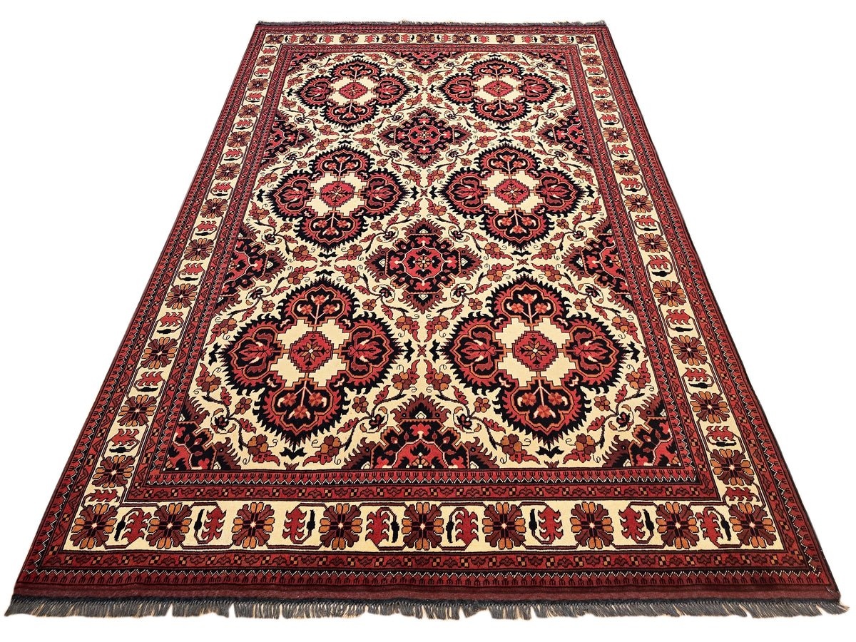 Large Afghan rug with cream field, red and navy ornamental medallions; fringed edges visible.