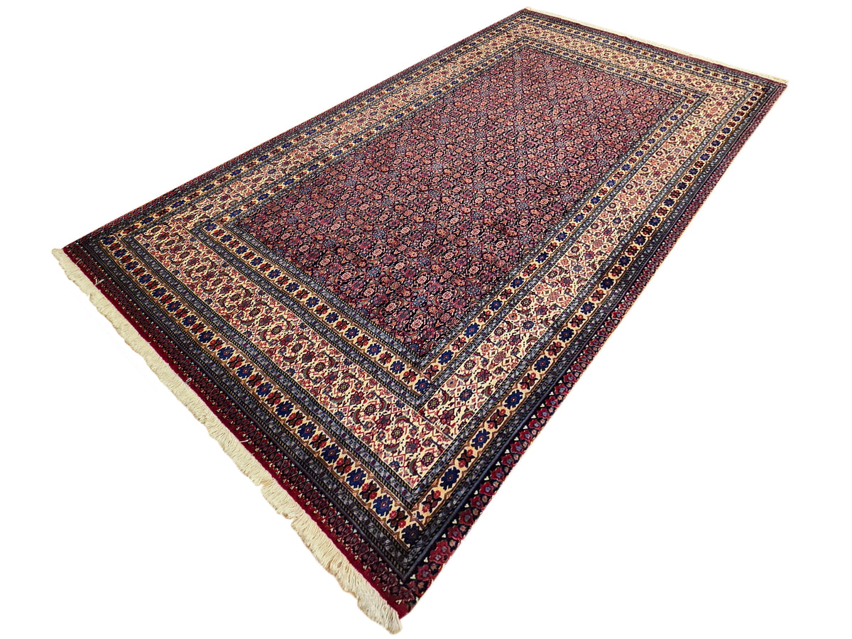 Red medallion area rug with dark border and cream fringe along the edges.