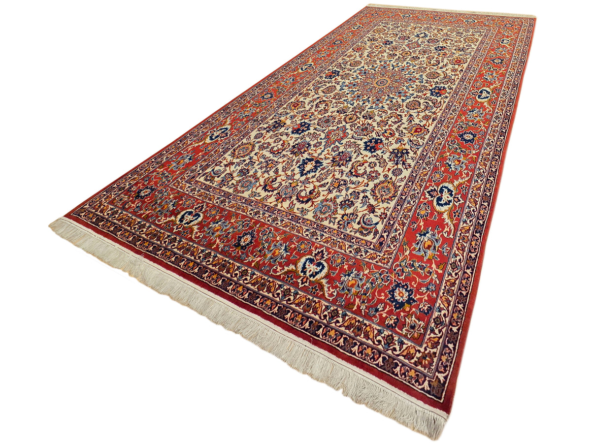 Diagonal view of red floral rug with cream medallion and fringed border edges