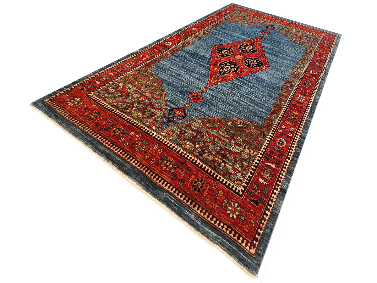 Geometric patterned area rug, blue ground with red diamond medallion and borders.