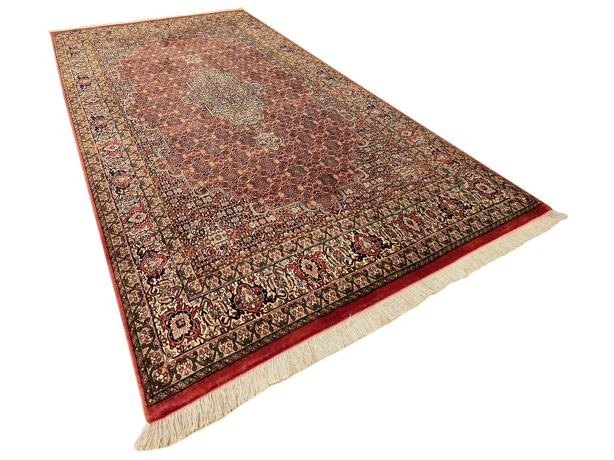 Bidjar rug angled view with warm rust tones, detailed pattern, dark border, and cream fringe.
