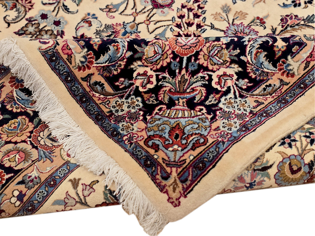 Rug corner detail with cream field, dark navy floral medallion, red accents, fringed edge