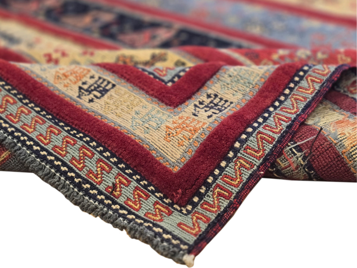 Rug corner detail with woven texture, red trim, cream medallions and multicolor pattern
