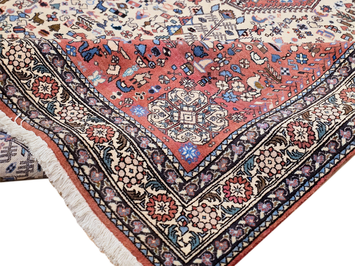 Rug corner with red center, cream and navy ornament border, fringed edge and vines