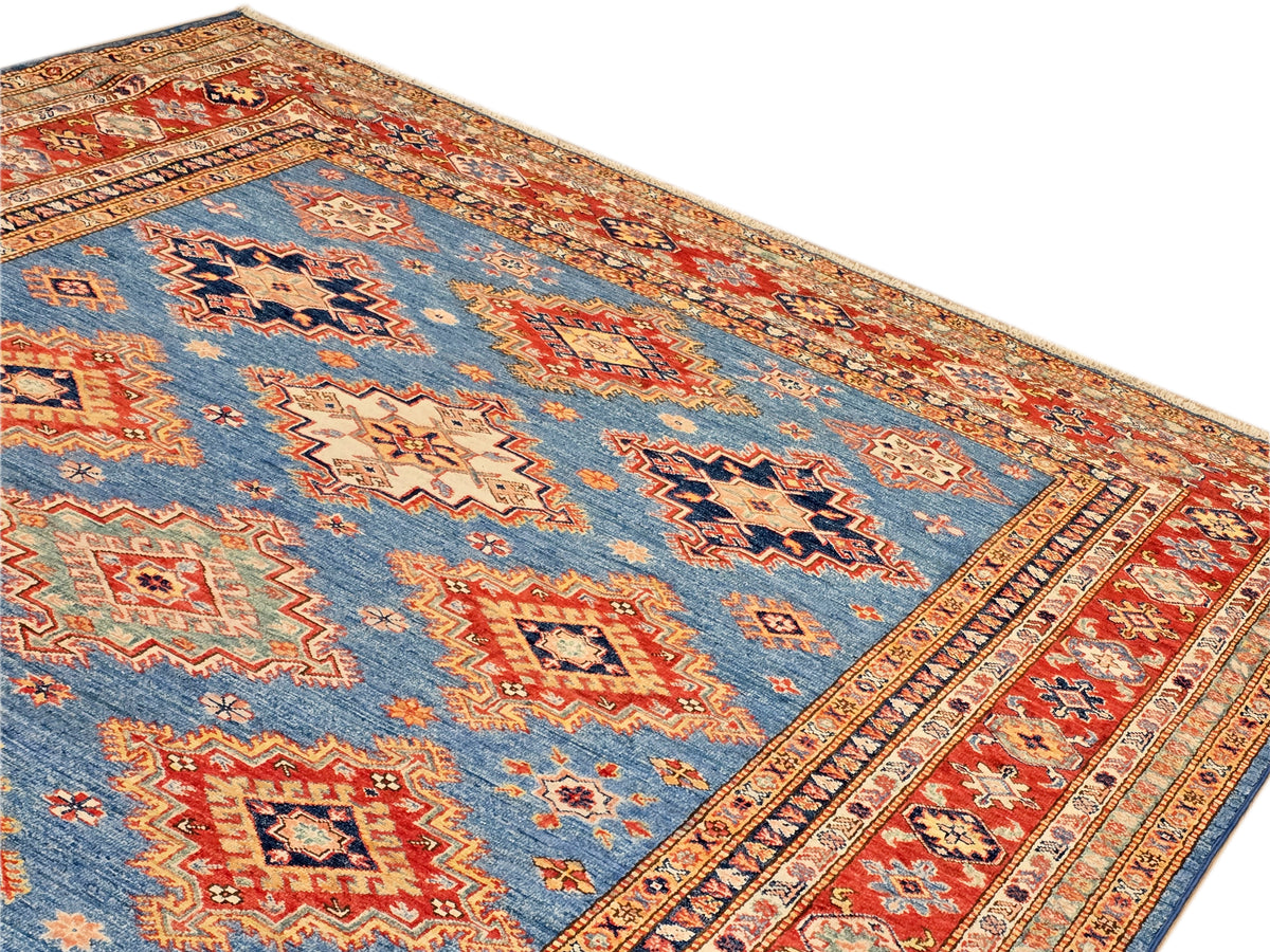 Rug corner view with blue field, red border stripe, and multicolor diamond motifs.