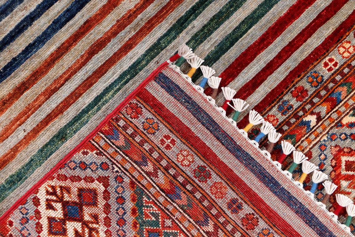 Rug corner close-up with diamond motif, striped bands, and white fringe