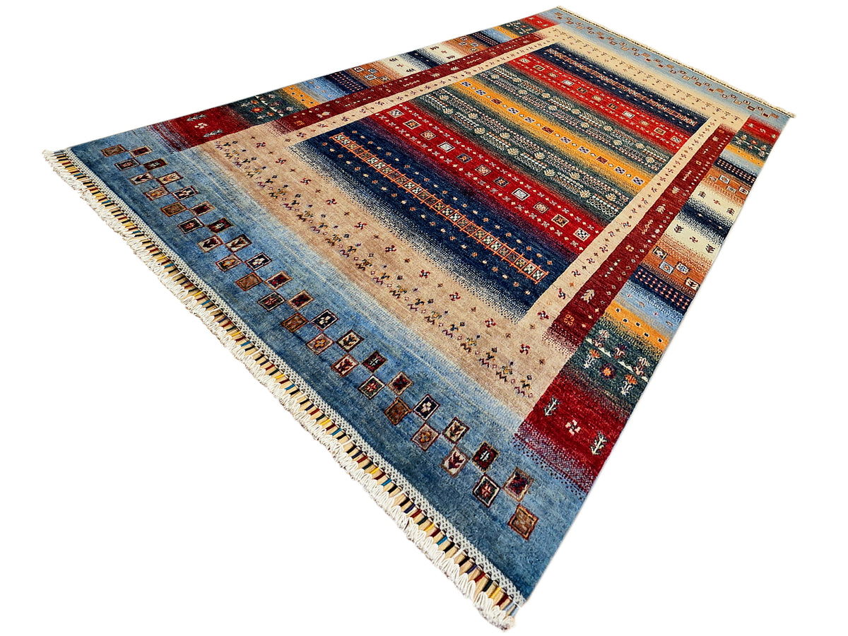 Geometric area rug with red, blue, and beige fields, diamond motifs, and fringe.