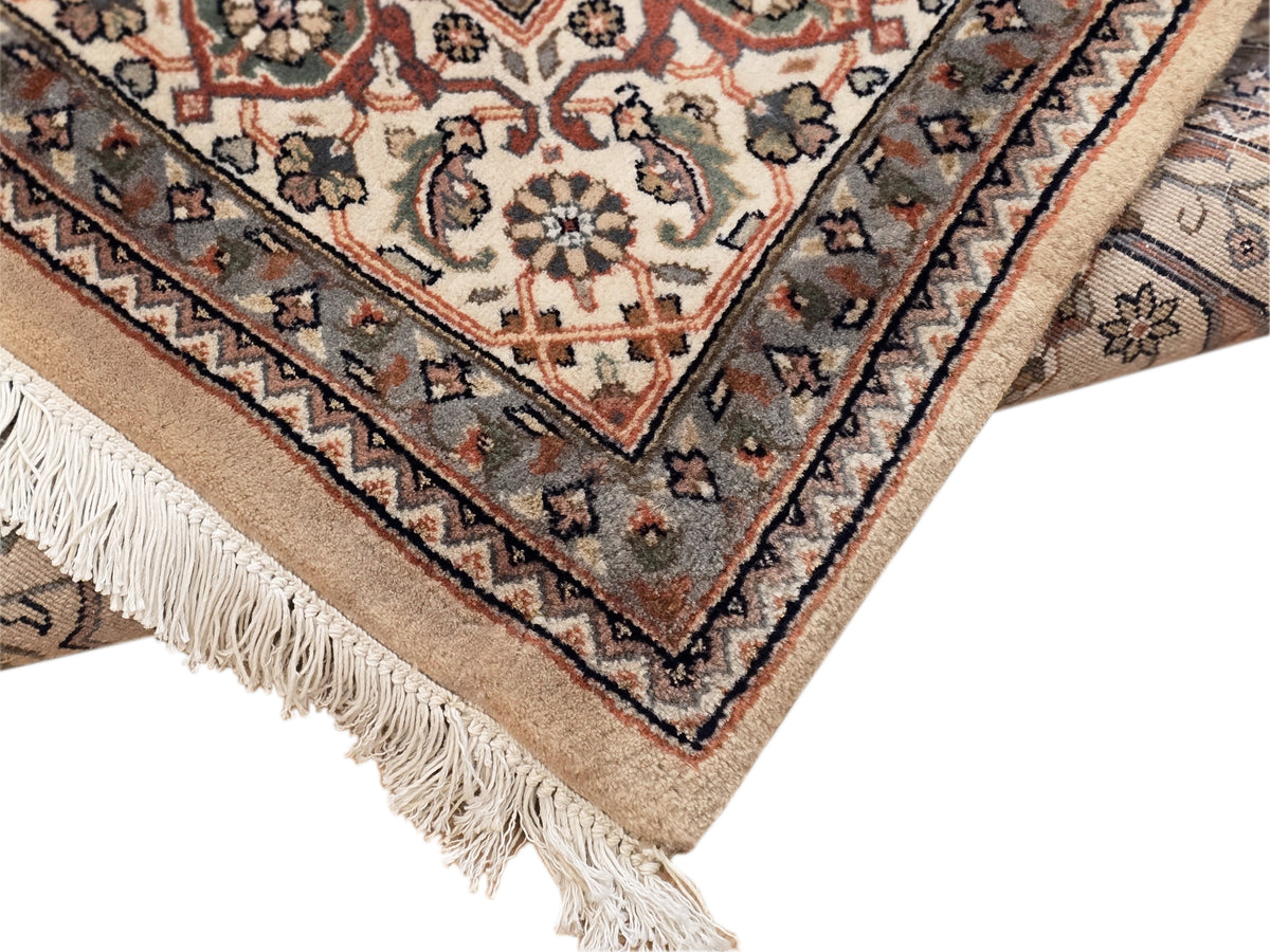 Khashan rug corner with textured beige ground, dark medallions, and fringe