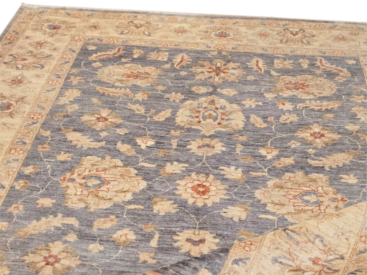 Close-up of ornate floral area rug with blue field, beige border, and vintage accents