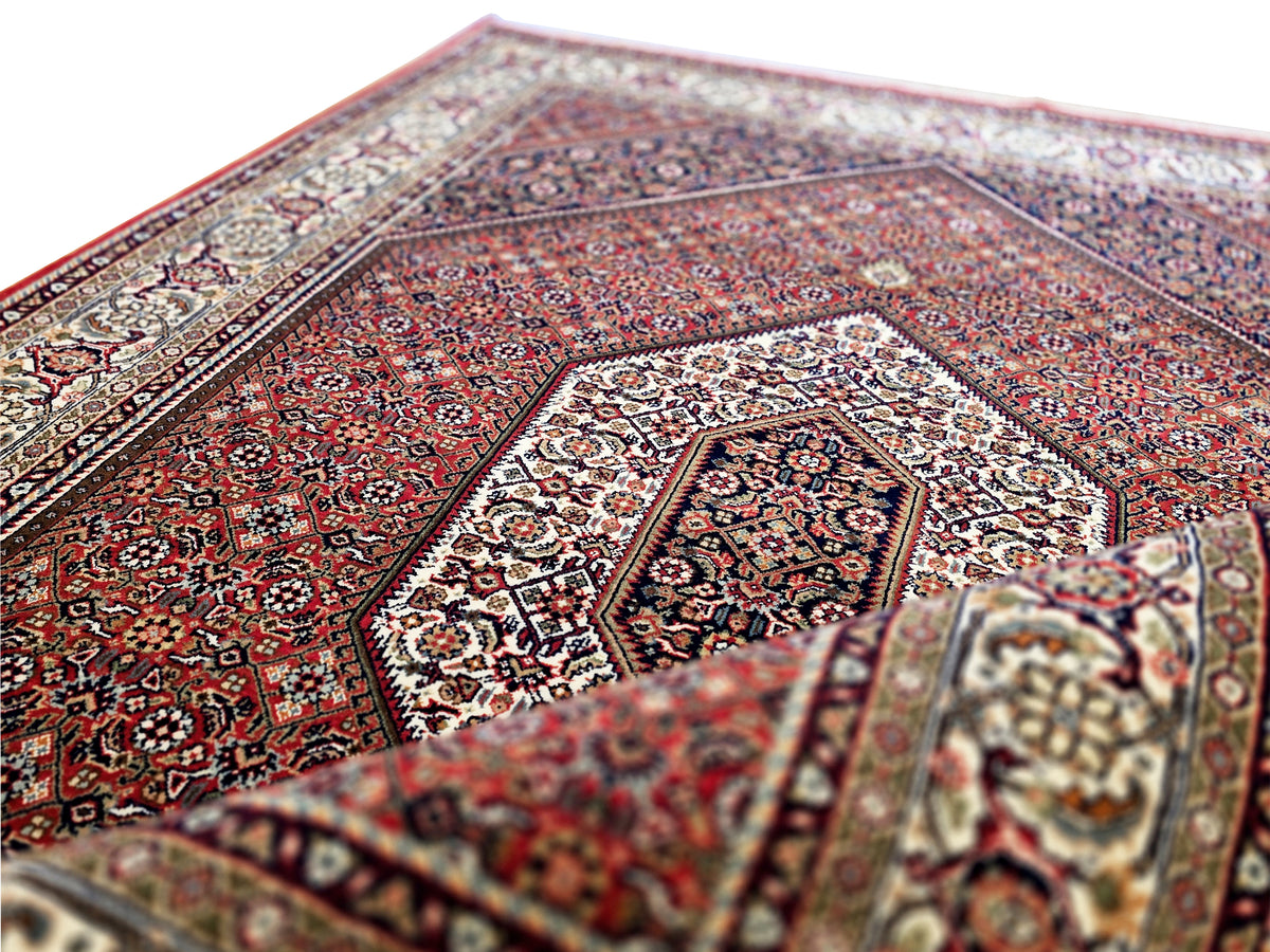 Woven red rug with central medallion and multicolor detailing, visible rug pile texture