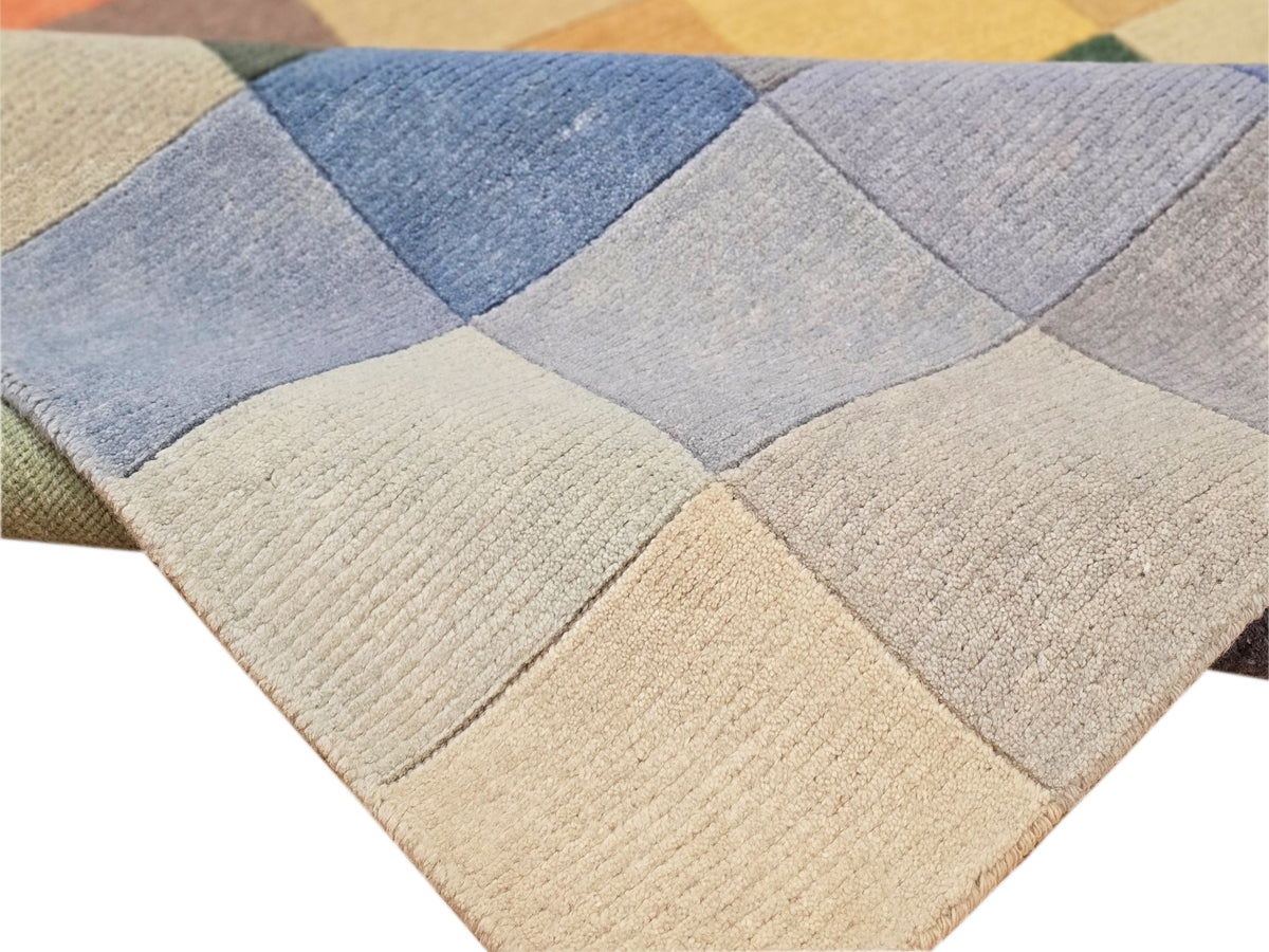 Multicolor patchwork area rug with textured blocks in blue, gray, and cream