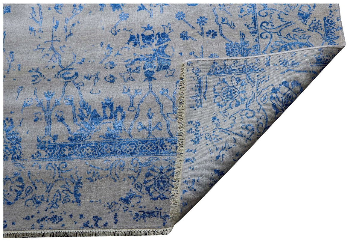 Blue and white patterned rug corner, shows diagonal fold and fringe trim