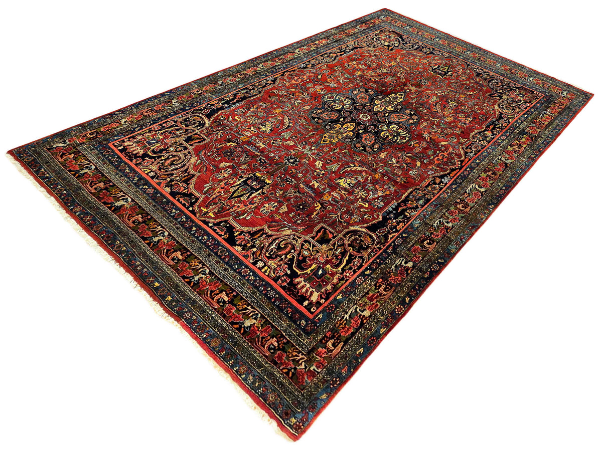 Red area rug with navy frame border, gold accents, and intricate floral detailing