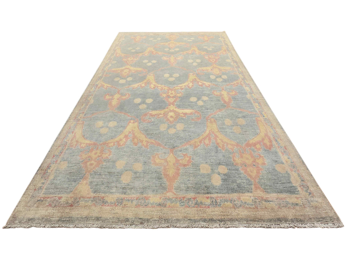 Light blue-gray rectangular rug with coral ornamental motif border and distressed texture