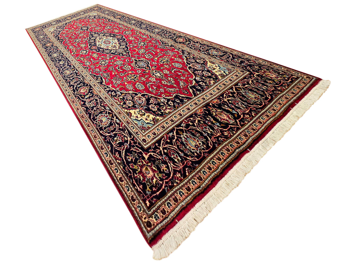 Kashan rug folded corner, red medallion on navy with cream fringe and trim
