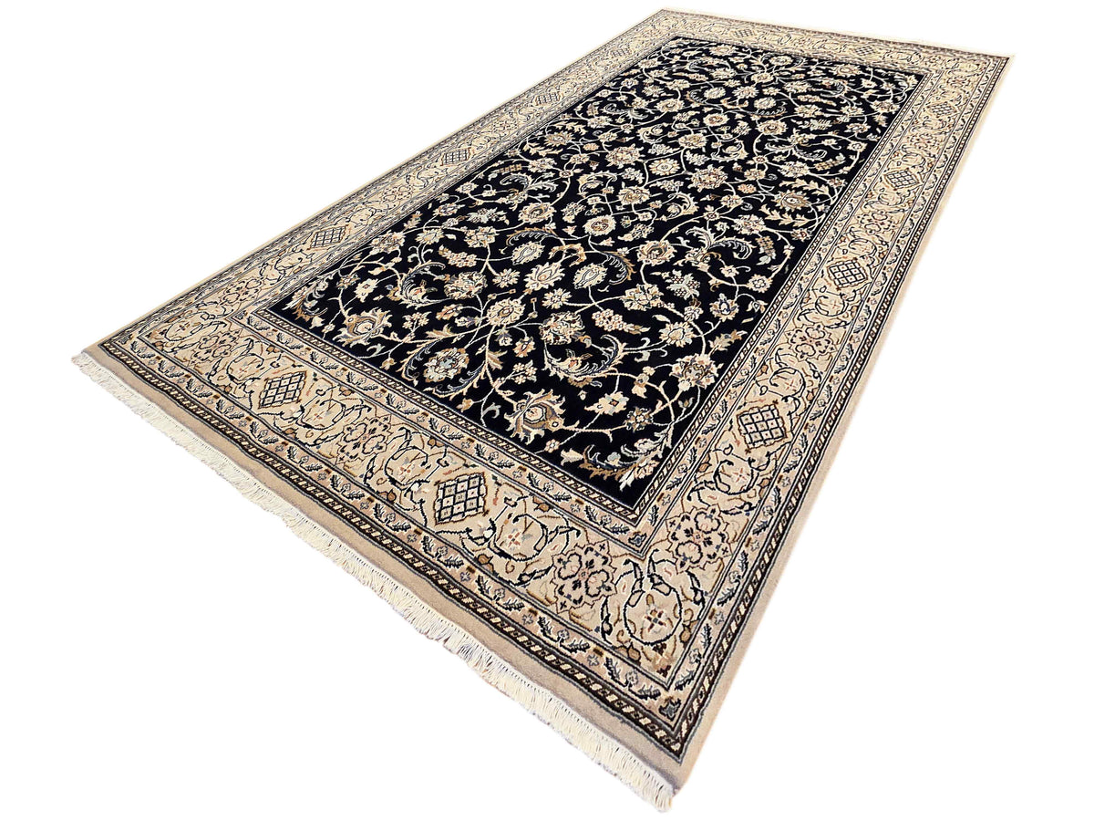 Navy Nain rug with cream and gold floral motifs, decorative border, fringe edges