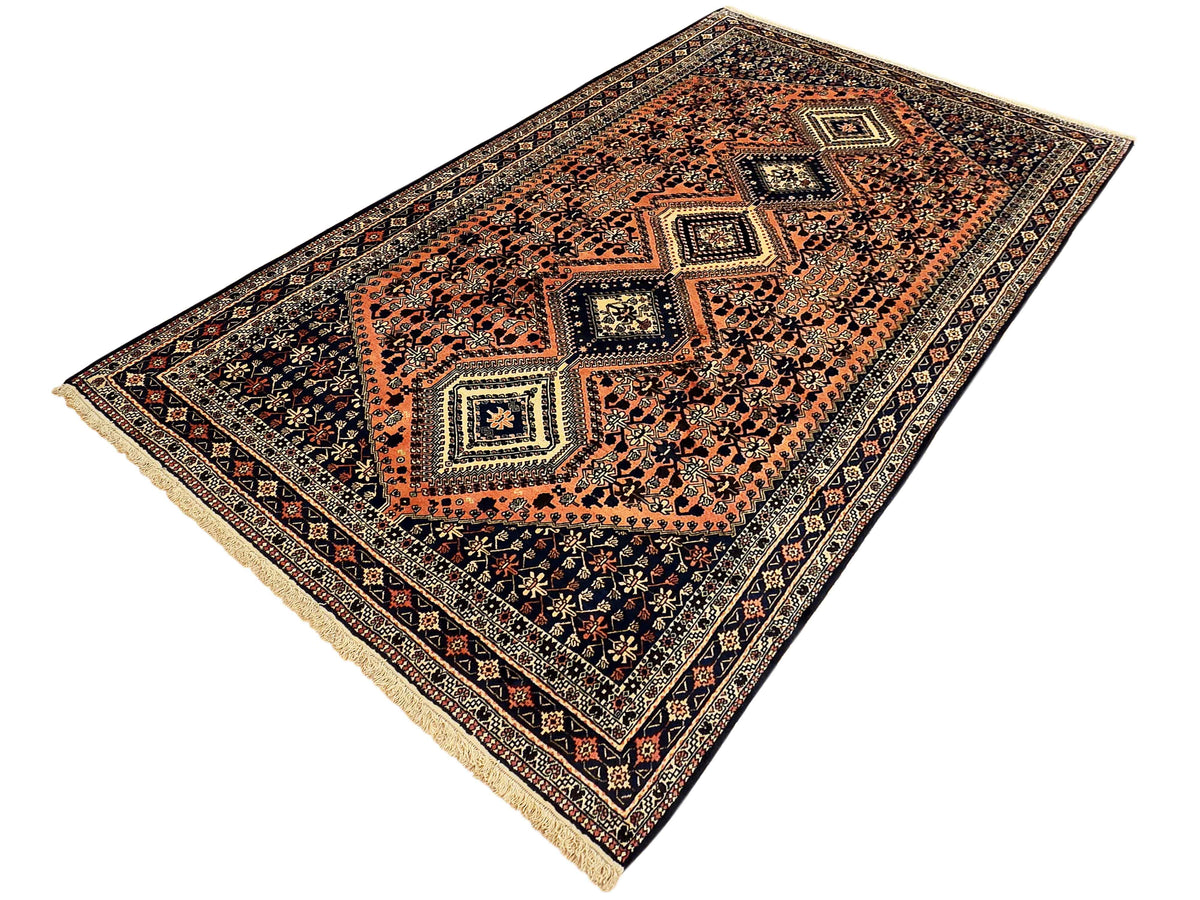 Orange, navy, and cream geometric medallion area rug with detailed border and fringe