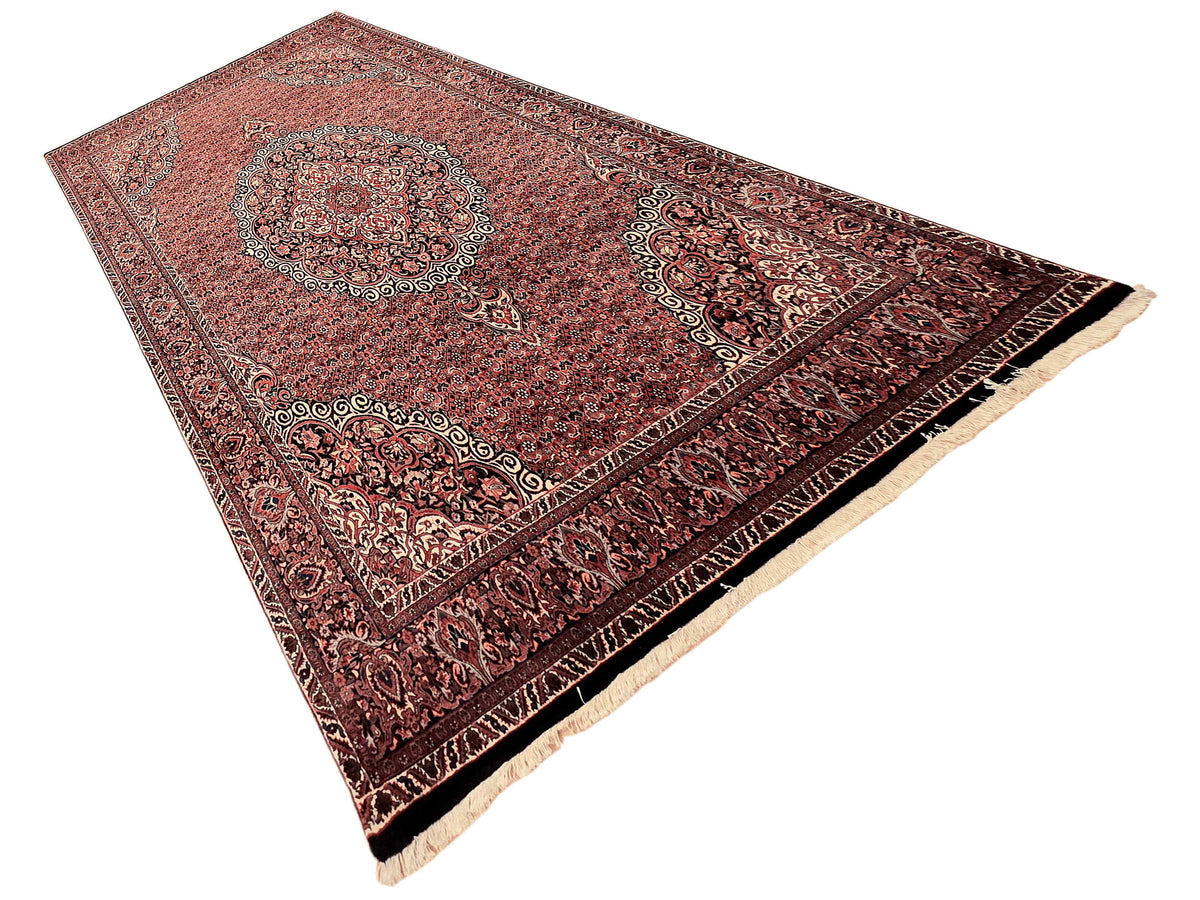 Rectangular terracotta rug with central medallion and cream fringe along edges