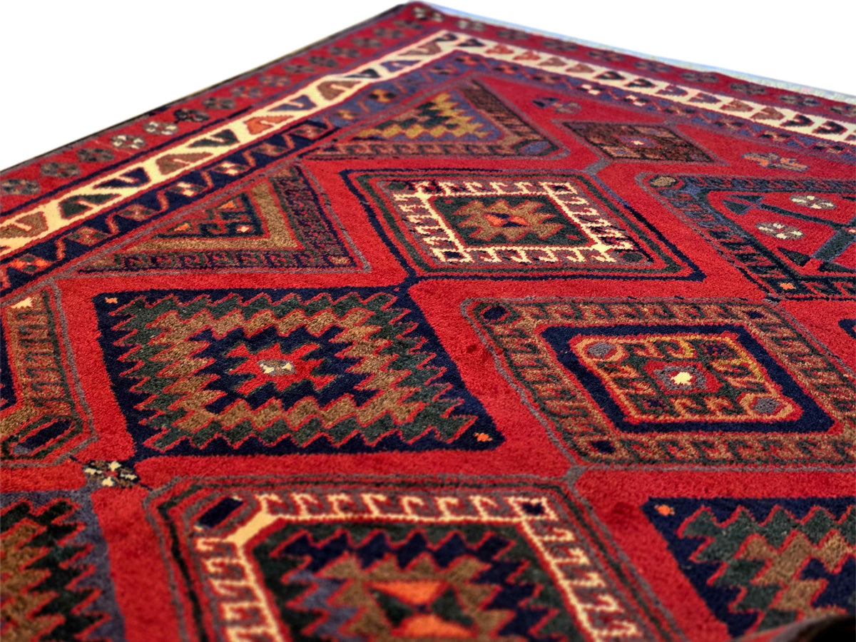 Geometric rug with red base, navy outlines, and multi-color motifs in blocks