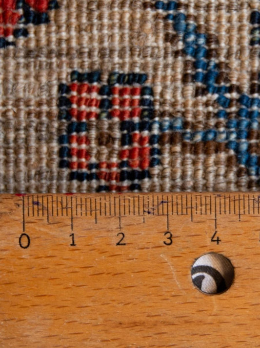 Beige textured rug close-up with red and blue square motifs