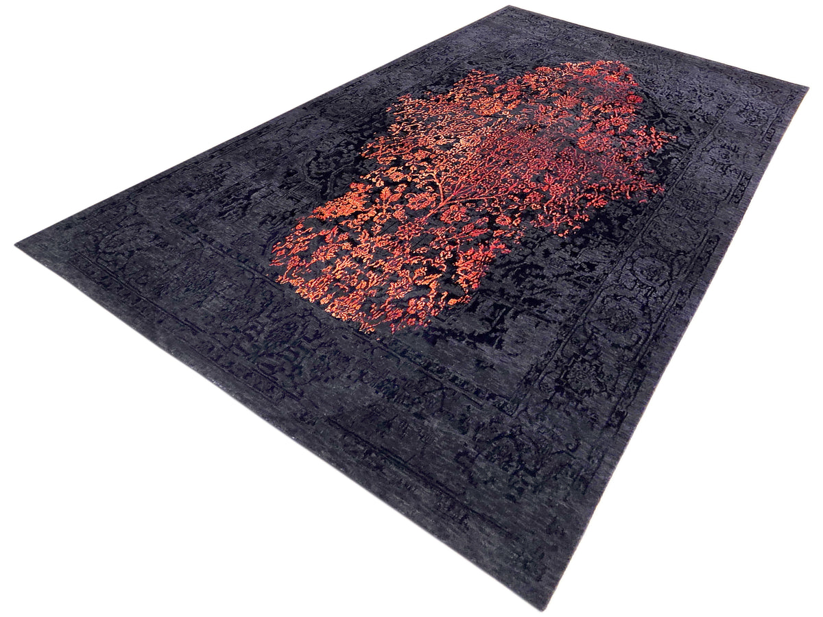 Dark navy rug with orange-red abstract medallion pattern, diagonally viewed