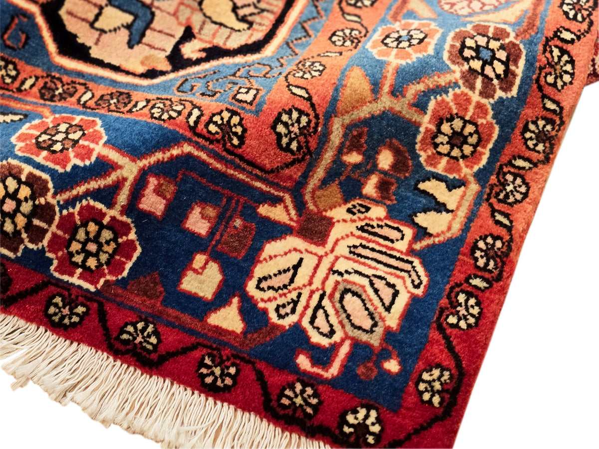 Nahawaand rug detail with geometric motifs in navy, red, and orange, cream accents, fringed edge.