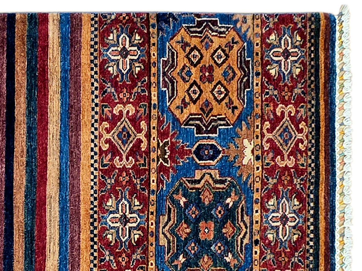 Woven rug detail showing vertical stripes, rosette motifs, and ornamental geometric panels