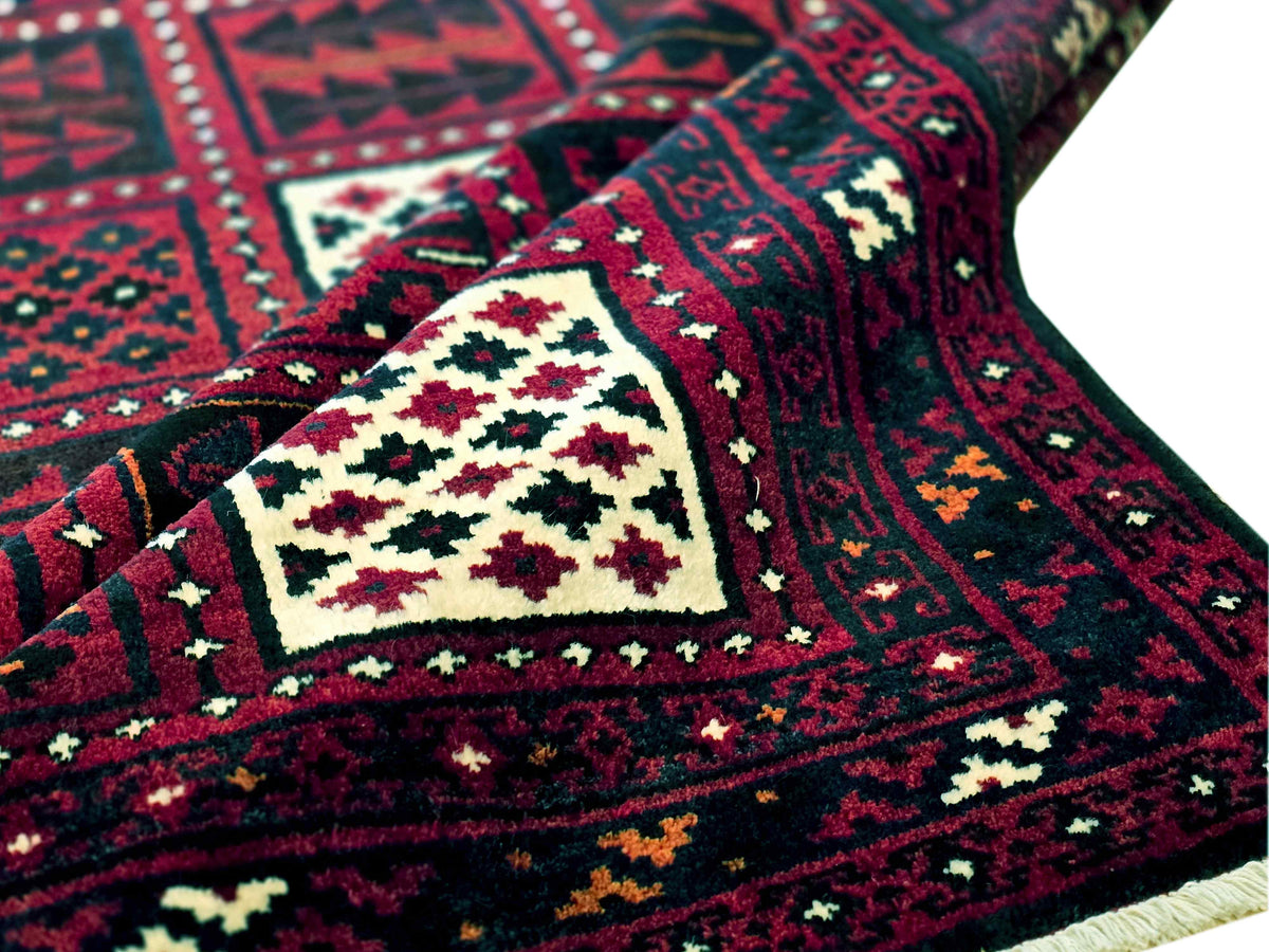 Persian-style rug with dark red field, cream medallion, and green accents; close-up detail.