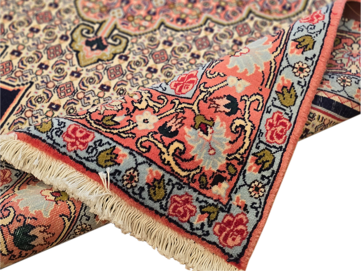 Close-up of patterned area rug edge with short fringe; red, blue, and cream details.