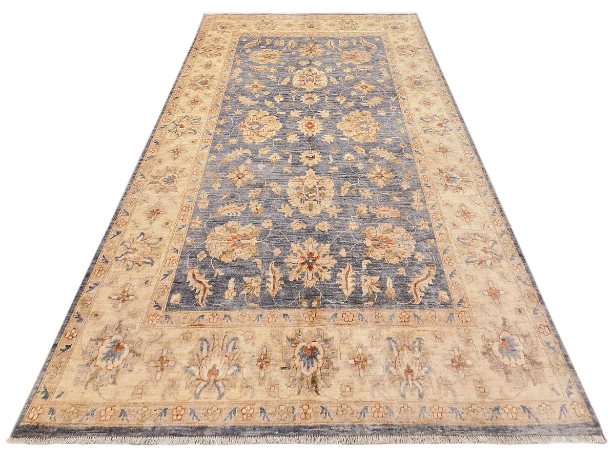 Rectangular floral area rug with blue central panel, beige border, and short fringe