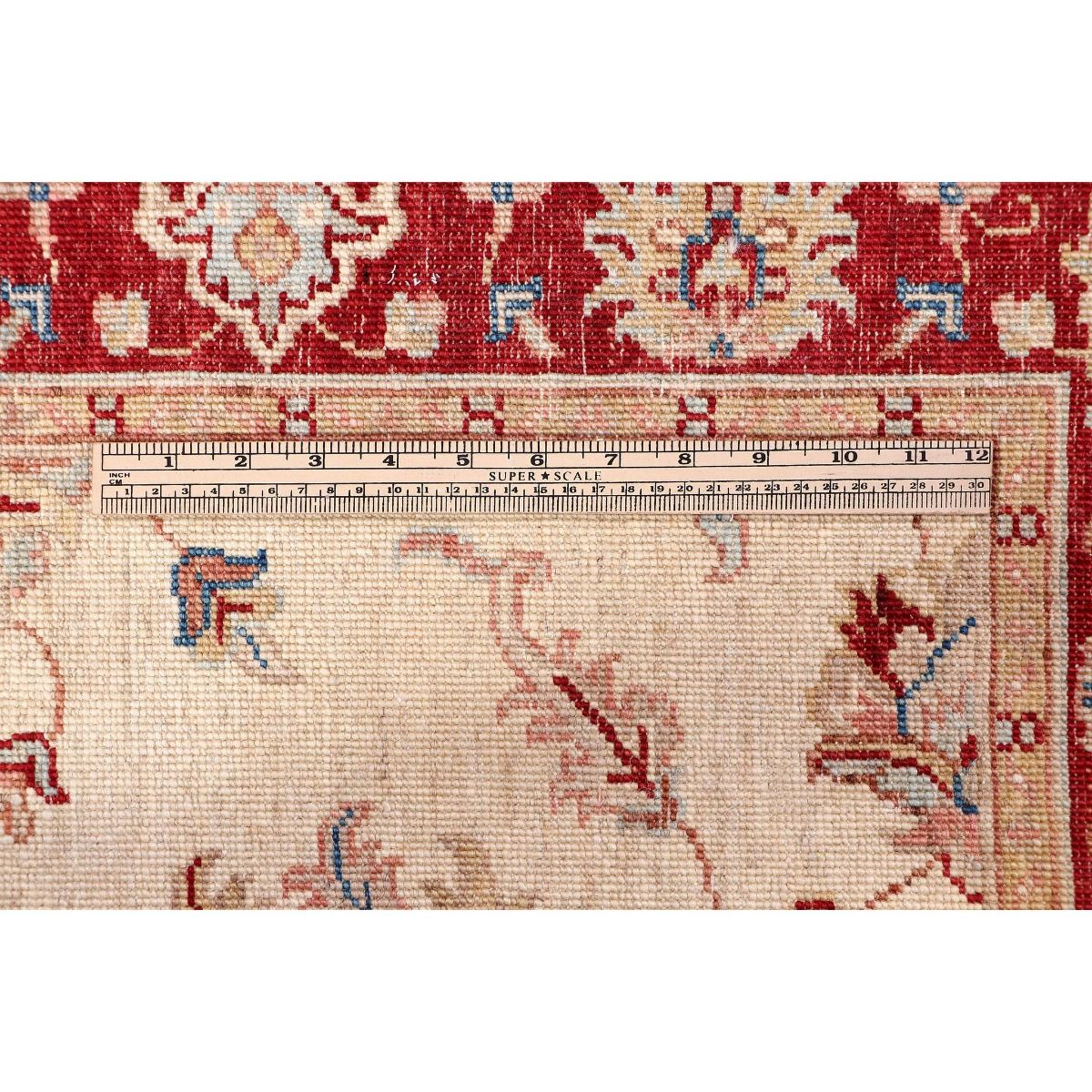 Carpet edge close-up with red trim, cream ground, and blue floral details.