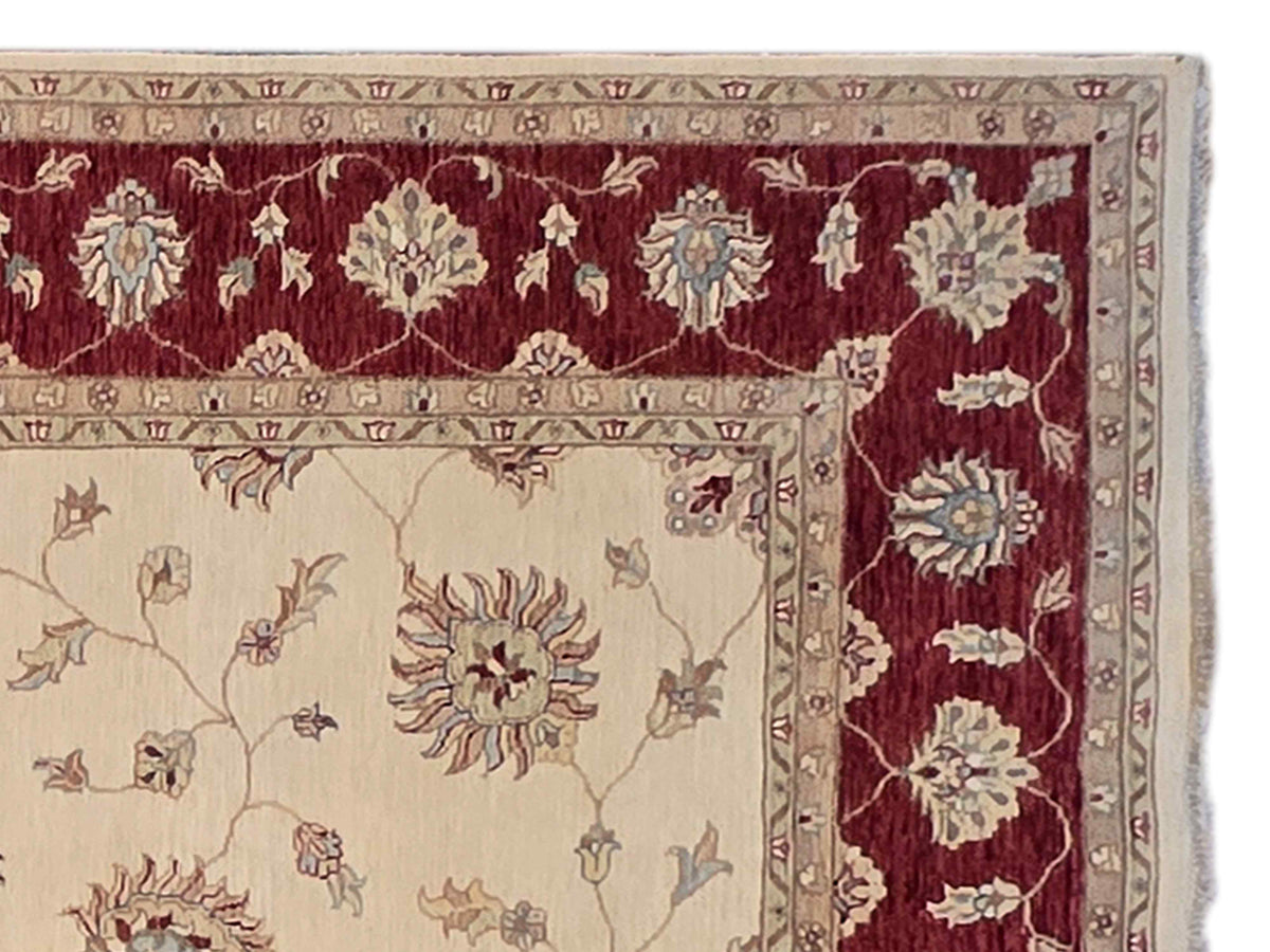 Rug corner detail with cream vines and flowers, burgundy band border, patterned trim